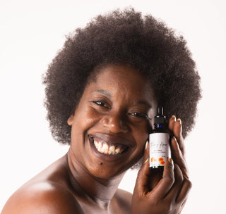 A woman smiles with Calendula and Geranium Facial Oil by Flor y Amor